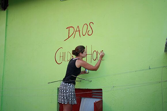 Mädchen mal Schriftzug auf Hauswand