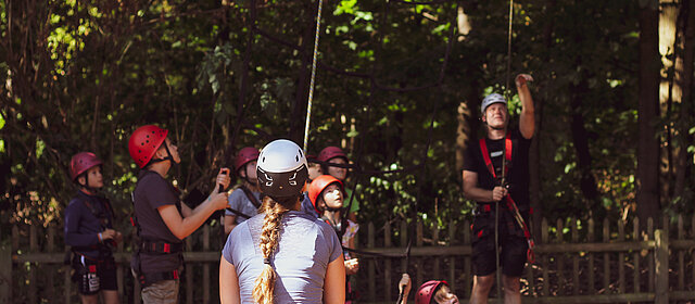 Hochseiilgarten Klettern junge Menschen Helm