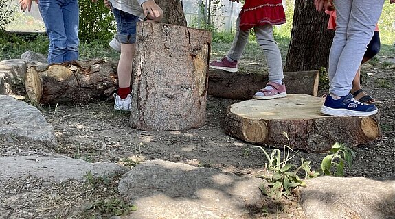 Kinderfüße auf Holzstämmen spielen